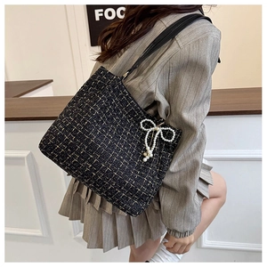 Detail der schwarzen Tweed-Tasche mit Metallic-Garn und Perlen-Schleifen-Anhänger