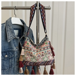 Close-up of bohemian woven square bag with colorful patterns and ethnic tassel details
