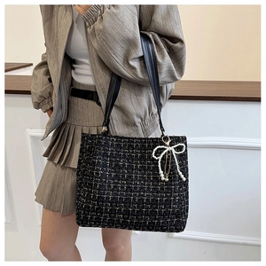 Detail der schwarzen Tweed-Handtasche mit Goldfaden, Perlen-Schleife und Lederriemen