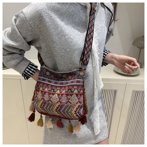 Close-up of ethnic embroidered crossbody bag with colorful tassels and patterned wide strap