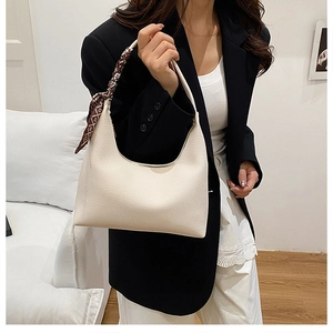 Détail d'un sac hobo blanc en cuir grainé avec un foulard en soie géométrique sur l'anse