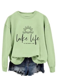 Detail of sage green sweatshirt featuring lake life graphic print and denim shorts