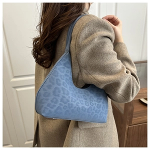 Detail einer blauen Schultertasche mit Leopardenmuster und eleganter Prägung