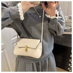 Dettaglio borsa a tracolla beige con elegante chiusura a rotazione in metallo oro ovale