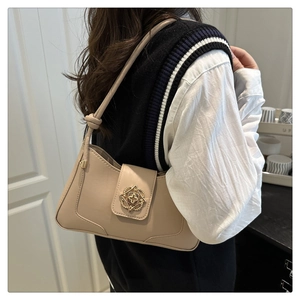Detail of beige leather underarm bag featuring a golden floral clasp and knotted strap