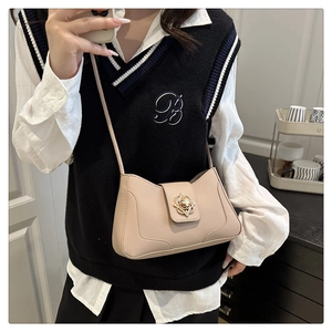 Detail of a chic beige leather crossbody bag with an elegant golden rose metal clasp