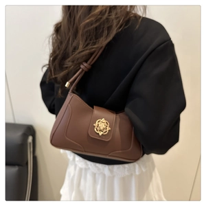 Detail view of caramel brown leather shoulder bag with decorative golden rose metal clasp