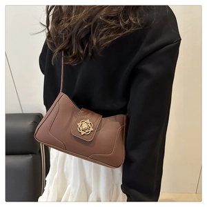 Detalle de bolso de hombro de cuero marrón vintage con hebilla metálica floral dorada