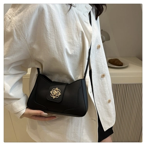 Detail of black vintage leather underarm bag with gold flower-shaped metal buckle