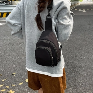 Minimalist black nylon crossbody bag featuring dual zipper compartments and adjustable strap