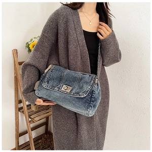 Nahaufnahme einer blauen Denim-Tasche mit silbernem Drehverschluss und Metallkettenriemen