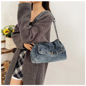 Nahaufnahme einer Denim-Umhängetasche mit Metallkettenriemen und Drehverschluss