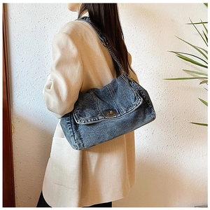 Detail einer Vintage-Denim-Umhängetasche mit Bronze-Drehverschluss und Kettenriemen