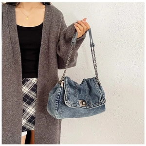 Detail der gewaschenen blauen Denim-Tasche mit silbernem Drehverschluss und Kettenriemen
