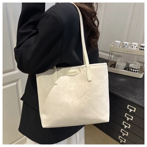 Close-up of cream leopard print tote bag with gold fashion label and slim straps