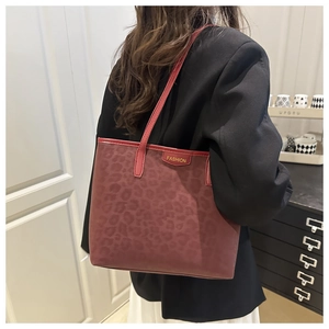 Macro detail of wine red suede tote bag featuring retro leopard print and leather trim