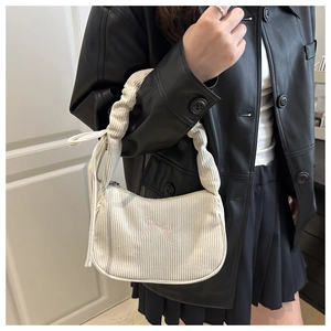 Détail du sac bandoulière en velours crème avec nœuds roses et bandoulière à volants