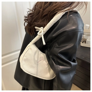 Detail of cream corduroy crescent bag with pink bow embroidery on black leather jacket