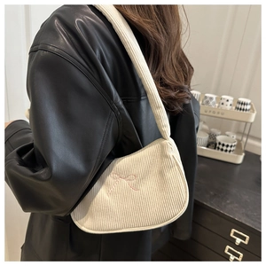 Détail du sac bandoulière en velours côtelé crème avec broderie nœud rose et texture
