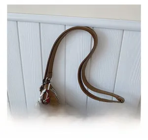 Close-up of brown textured tote bag handle with a cute brown plush bear charm detail