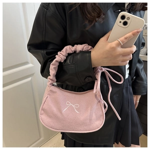 Détail d'un sac à main en velours rose avec broderie nœud blanc et poignée froncée mode