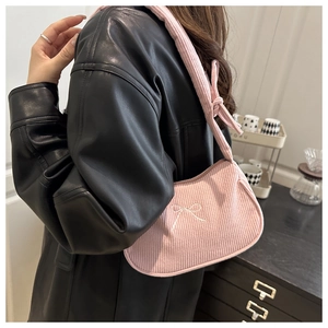 Detail of pink corduroy shoulder bag featuring white bow embroidery and knotted strap