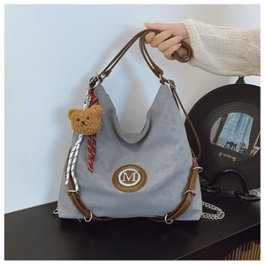 Detail of grey nylon tote bag with brown leather straps and metallic M logo accent