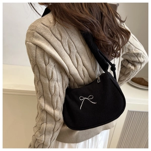 Détail du sac hobo en velours côtelé noir avec broderie nœud argenté porté par modèle