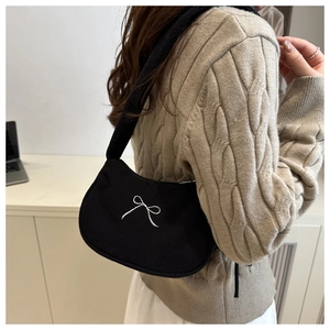 Close-up of black corduroy shoulder bag featuring white bow embroidery and soft texture