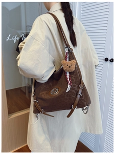Detail of leopard print tote bag with metal M logo and cute plush bear charm on model