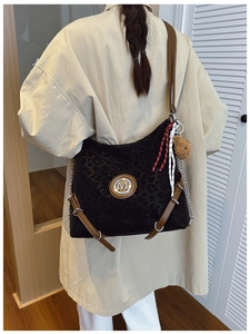 Rear view of a large leopard print shoulder bag on a beige trench coat with metal logo