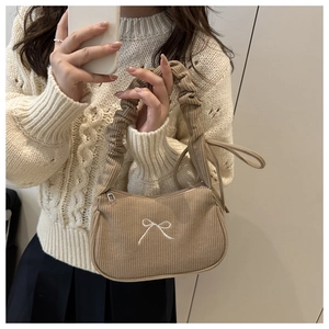 Detail of khaki corduroy handbag with white bow embroidery and pleated handle design