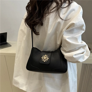 Bolso de hombro vintage de cuero sintético negro con cierre dorado en una modelo