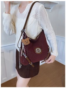 Macro view of burgundy hobo bag with leopard texture, metal M logo, and bear charm