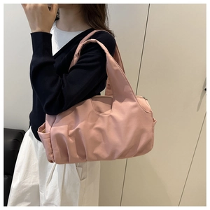 Détail du sac à bandoulière plissé en nylon rose clair avec large anse sur mannequin