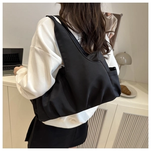 Gros plan d'un sac à main noir plissé en nylon porté à l'épaule dans un cadre moderne