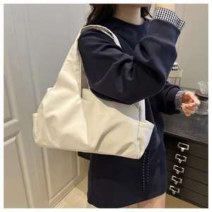 Détail d'un sac cabas plissé en nylon blanc crème montrant la poche latérale et la texture