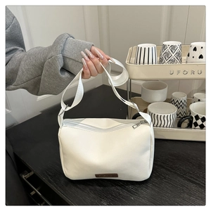 Détail d'un sac bandoulière blanc minimaliste avec une étiquette en cuir marron FASHION