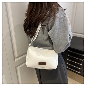 Détail du sac bandoulière blanc élégant avec patch FASHION porté par un mannequin