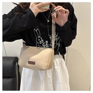 Détail de la bandoulière en nylon beige avec étiquette en cuir et sangle large
