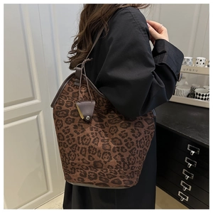 Detailed close-up of leopard print tote bag with brown leather straps worn by model