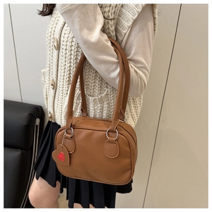 Borsa a tracolla marrone martellata con ciondolo a cuore indossata per mostrare il fit