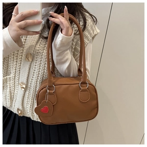 Detailed macro view of the brown lychee pattern texture and heart charm on the handbag