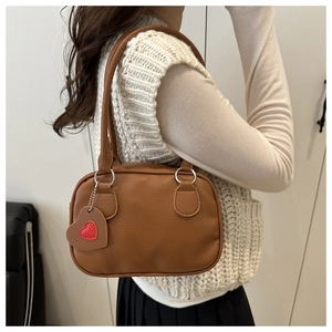 Detail of caramel lychee grain leather tote bag with heart charm and silver hardware