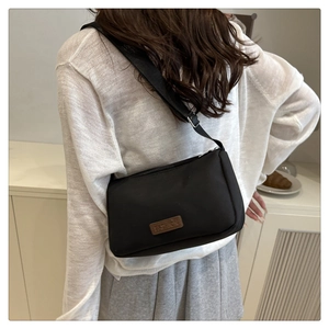 Vue arrière d'un mannequin portant un sac bandoulière en nylon noir avec sangle