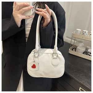 Close-up of a white lychee grain handbag featuring a decorative red heart charm detail