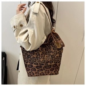 Borsa tote leopardata con manici in pelle marrone indossata da modella in cappotto