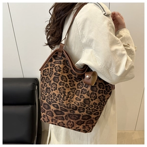 Close-up of leopard print tote bag with brown leather straps worn with a beige trench coat