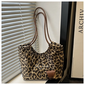 Detail of leopard print suede tote bag with brown handles and mini charm accessory