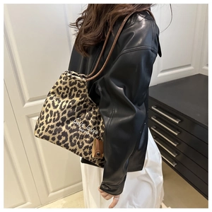 Leopard print canvas tote bag with brown leather straps shown on model in home setting